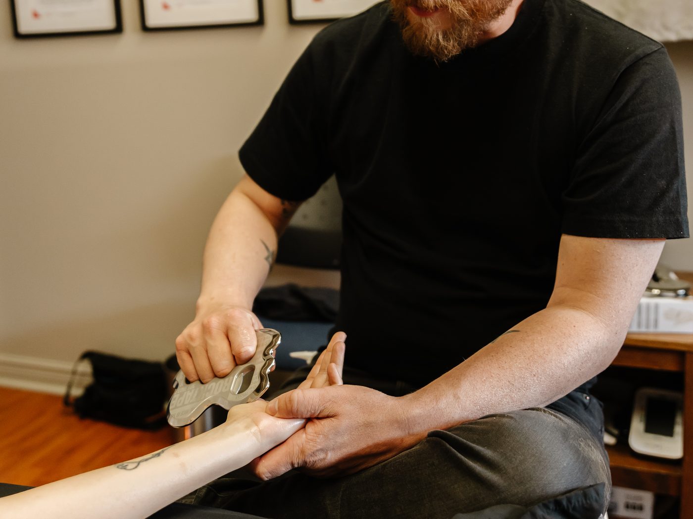 IASTM treatment, stainless steel instrument applied to the forearm.