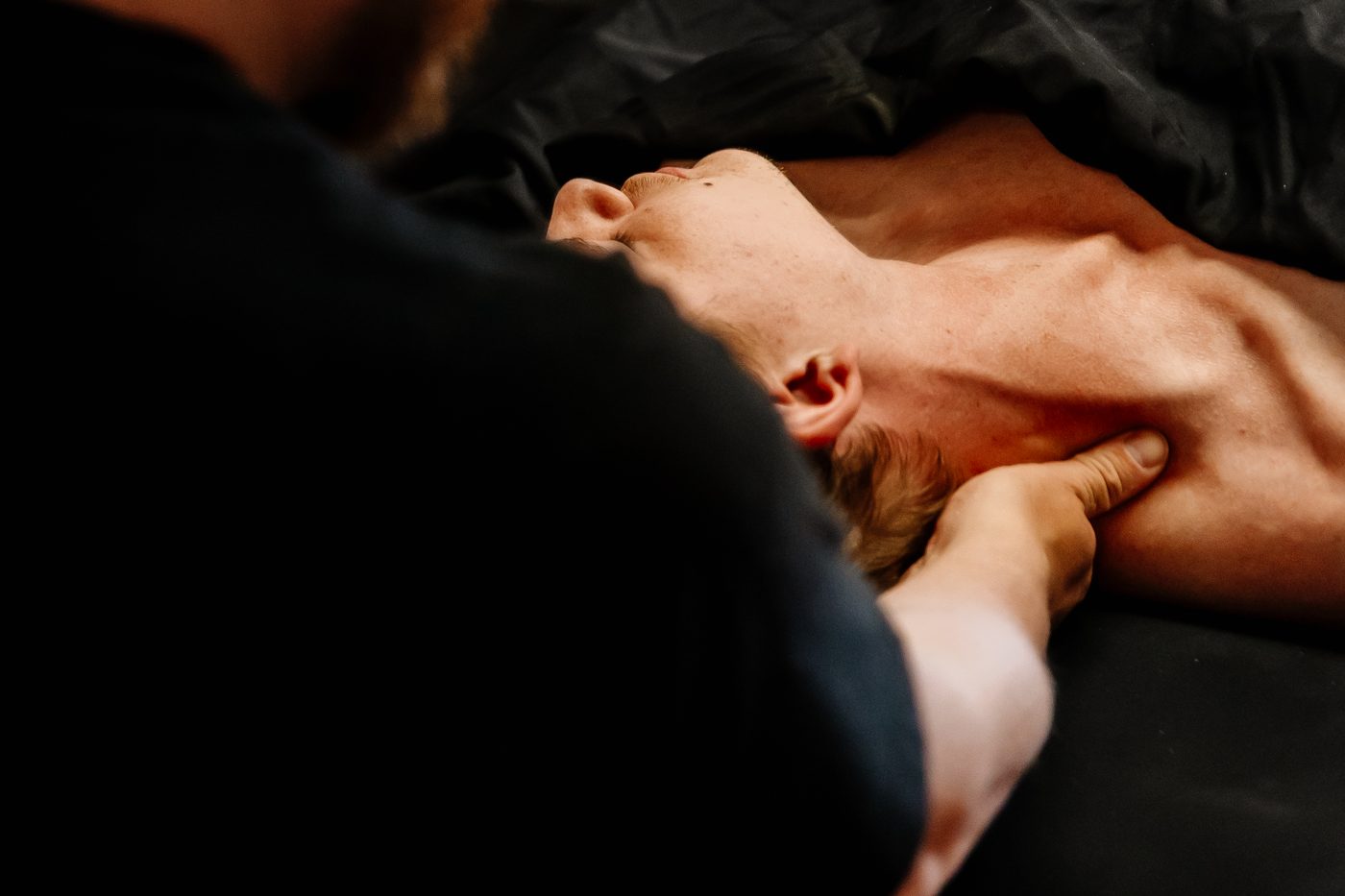 Mathieu Boudreau, RMT, providing hands-on neck treatment to a client lying on the massage table.