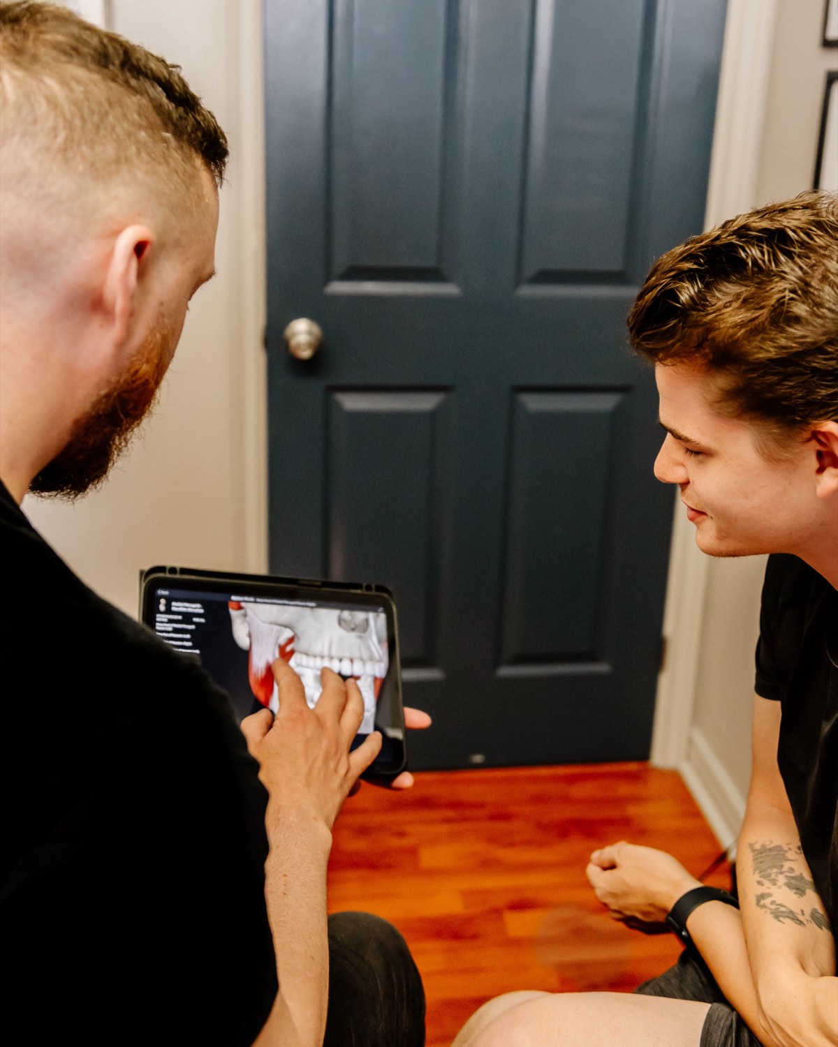 Mathieu Boudreau, RMT, using an iPad to explain anatomy and treatment options to a fully clothed client in his Moncton clinic.